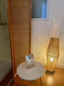 a table with a lamp and a table with a picture on it at Chambre privé à deux pas de la gare in Montauban-de-Bretagne