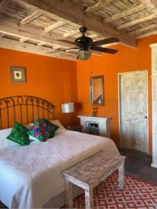 a bedroom with orange walls and a bed and a ceiling fan at View Hotel Boutique in San Miguel de Allende