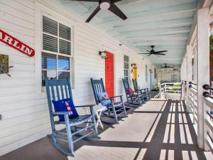 een rij blauwe stoelen op een veranda met een rode deur bij Beach Walk 4 in Tybee Island