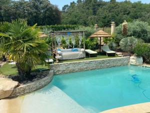 una piscina en un patio trasero con una cama y un columpio en D’ici et d’ailleurs, en Beaumont-de-Pertuis