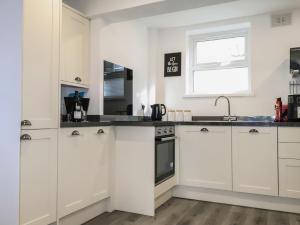 a kitchen with white cabinets and a sink and a window at Henllys in Harlech