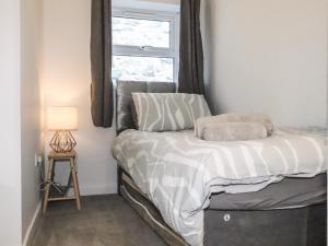 Dormitorio pequeño con cama y ventana en Henllys, en Harlech