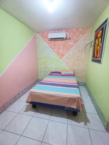 Cama pequeña en habitación con paredes coloridas en Hostal Venecia -Tu casa en Manta. en Manta