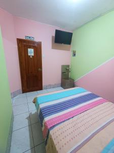 曼塔的住宿－Hostal Venecia -Tu casa en Manta.，粉红色客房内的一间卧室,配有一张床