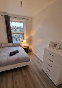 a bedroom with a bed and a dresser and a window at Comfortable 2 bedrooms flat in Oval Central London in London