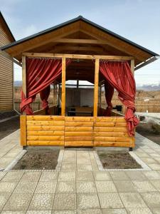 ボステリにあるWooD_House_Issyk-Kulの赤いカーテン付きの木製の展望台