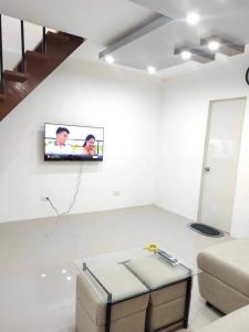 uma sala de estar com televisão numa parede branca em REGIE Homestay Vigan City em Aggay