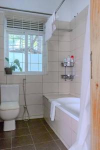 uma casa de banho com uma banheira, um WC e uma janela. em The Greenleaf Luxury BnB -Lubowa em Kampala