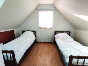 2 camas en una habitación con ventana en Maison à 200m de la plage avec jardin clos sur l'ILE GRANDE - Réf 283, en Pleumeur-Bodou