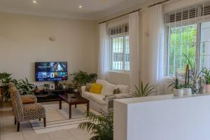 sala de estar con sofá y TV en The Greenleaf Luxury BnB -Lubowa, en Kampala