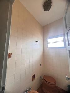 a bathroom with a toilet and a window at Casa para temporada baixada santista in Solemar