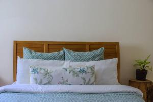 a bed with a wooden headboard with pillows at The Greenleaf Luxury BnB -Lubowa in Kampala