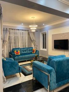 ein Wohnzimmer mit blauen Sofas und einem TV in der Unterkunft The Crib in Munyonyo in Kampala