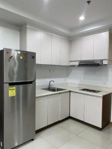 uma cozinha com um frigorífico de aço inoxidável e armários brancos em SnugglePod Condotel - Grand Riviera Suites, US Embassy Manila, Roxas Blvd em Manila