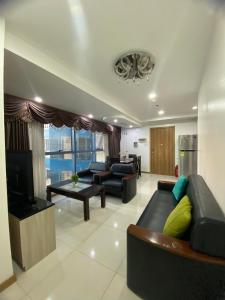 uma sala de estar com sofás pretos e uma televisão em SnugglePod Condotel - Grand Riviera Suites, US Embassy Manila, Roxas Blvd em Manila