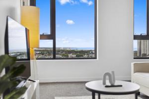 een woonkamer met grote ramen en een tafel bij Vibrant Southbank 2 bedroom Apartment in Melbourne