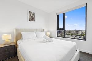 een slaapkamer met een wit bed en een groot raam bij Vibrant Southbank 2 bedroom Apartment in Melbourne
