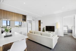 een witte woonkamer met een witte bank en een keuken bij Vibrant Southbank 2 bedroom Apartment in Melbourne