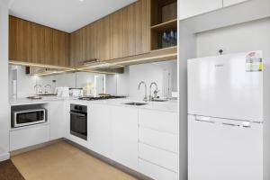 een keuken met witte kasten en een witte koelkast bij Vibrant Southbank 2 bedroom Apartment in Melbourne