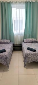 two beds in a room with blue curtains at MARINA ROOMS in Alicante
