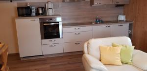 a kitchen with white cabinets and a couch in a room at Ferienhaus Breit in Eppenschlag