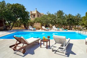 una piscina con 2 tumbonas y una mesa junto a la piscina en Unique Venetian Style Villa "Leniko" in Crete, en Atsipopoulo