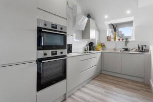 a white kitchen with a stove and a microwave at Sea views, Beachbreeze, Pet friendly, Private parking in Teignmouth