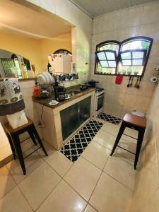 uma cozinha com fogão e duas cadeiras em Green House saqua em Saquarema