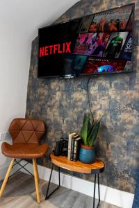 a chair and a table with a tv on a wall at Sea views, Beachbreeze, Pet friendly, Private parking in Teignmouth