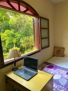 einen Laptop auf einem Schreibtisch neben einem Fenster in der Unterkunft Green House saqua in Saquarema
