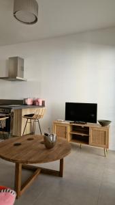 uma sala de estar com uma mesa e uma televisão de ecrã plano em Le Malakoff em Sérignan