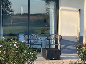 2 chaises assises sur la terrasse couverte avant d'une maison dans l'établissement Hotel Le Clos De La Prairie, à Gouy-Saint-André