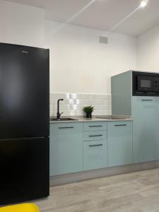 a kitchen with white cabinets and a black refrigerator at Apartamento Chic Centro in Dos Hermanas