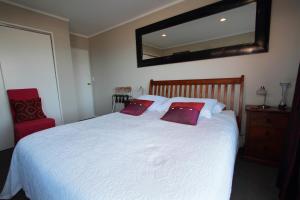 a bedroom with a white bed with two red pillows at Pacific View Bed and Breakfast in Wellington