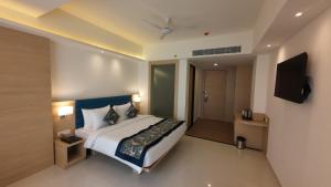 een slaapkamer met een bed en een flatscreen-tv bij HOTEL SURYA GRAND in Siliguri