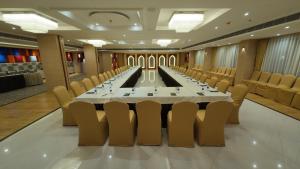 HOTEL SURYA GRAND في سيليغري: قاعة اجتماعات كبيرة مع طاولة وكراسي طويلة
