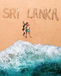 twee mensen springen in het zand op het strand bij Aloe Vera villa in Negombo