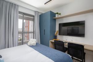 a hotel room with a bed and a desk and a tv at 360 My Moema in São Paulo