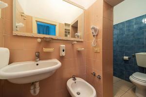 a bathroom with a sink and a toilet and a mirror at Hotel Belmare in Porto Azzurro