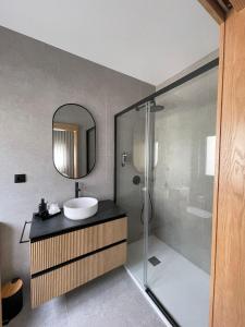 a bathroom with a sink and a shower with a mirror at OPORTO Suites in Moreira