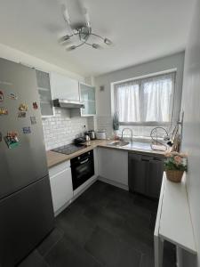 La cuisine est équipée d'un réfrigérateur et d'un évier. dans l'établissement O'Rits Paris - Magnifique appartement proche Paris, à Rueil-Malmaison