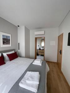 una camera da letto con un grande letto bianco con cuscini rossi di OPORTO Suites a Moreira