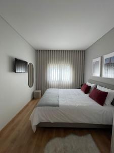 a bedroom with a large white bed with red pillows at OPORTO Suites in Moreira