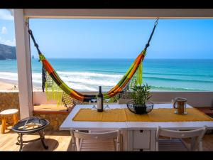 a hammock on a table with a view of the ocean at 2 bedrooms house at Aljezur 100 m away from the beach with sea view furnished terrace and wifi in Aljezur