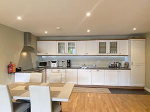 een keuken met witte kasten en een houten tafel bij Apartment 453 - Clifden in Clifden