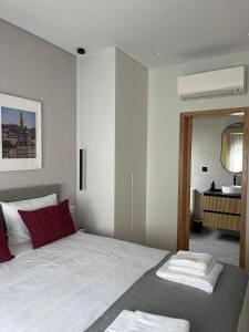 1 dormitorio con 1 cama blanca grande con almohadas rojas en OPORTO Suites en Moreira