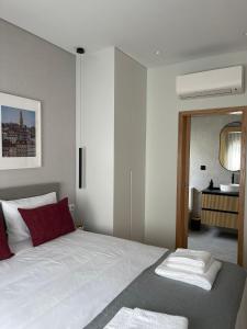 1 dormitorio con 1 cama blanca grande con almohadas rojas en OPORTO Suites, en Moreira