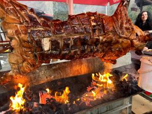 a pork roast being cooked on a flaming grill at Lacul de argint in Gura Rîului