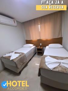 two beds in a room with a hotel room at Hotel Accordes in Campo Grande