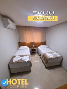 a hotel room with two beds and a sign that reads hotelaccoosa at Hotel Accordes in Campo Grande